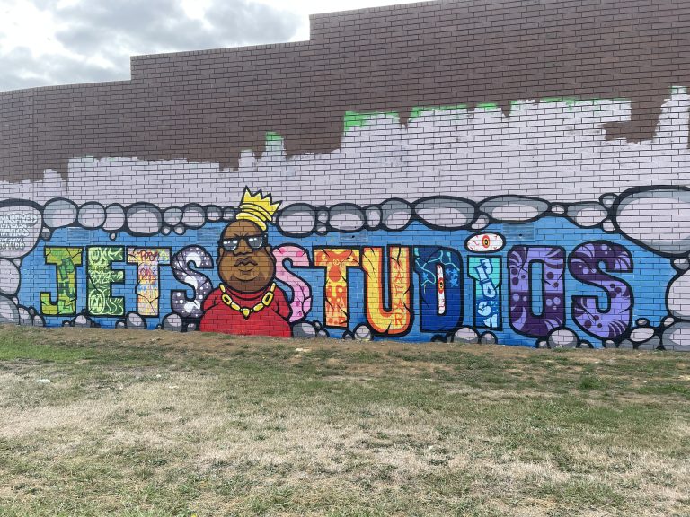a mural spray painted on a brick wass reading "Jets Studios"with an animated Biggie in between words