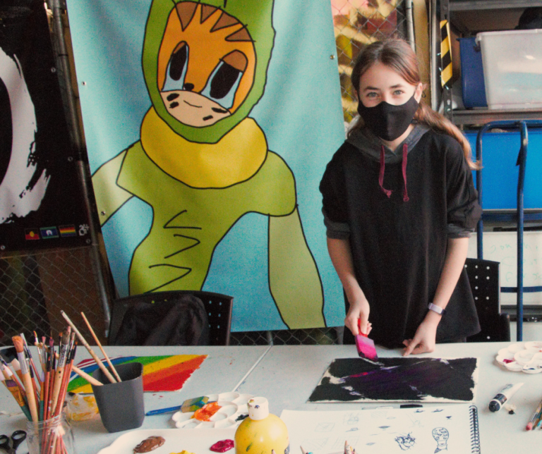 young person creating art while wearing a mask