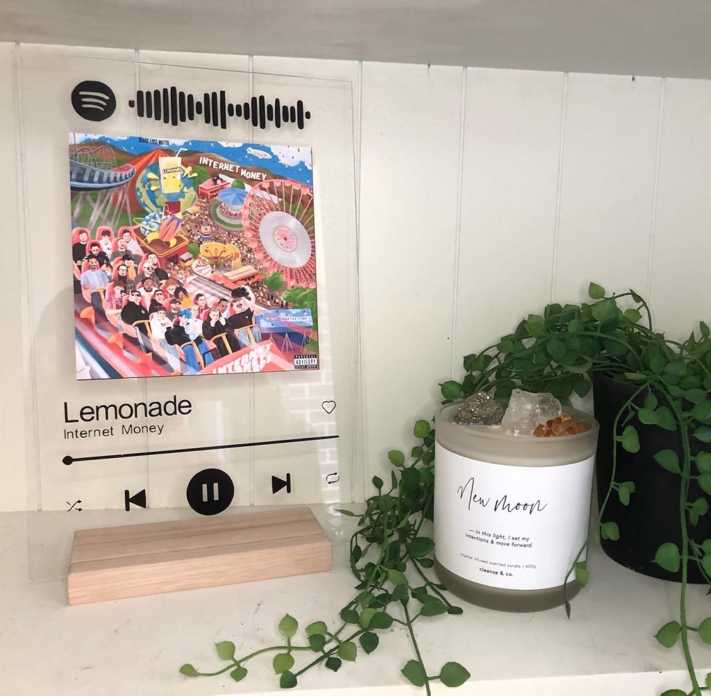 a Glass Spotify plaque next to a small house plant and white candle