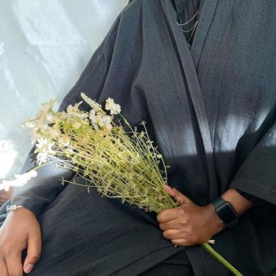 Shona sitting with a handful of small flowers while modelling an abayas
